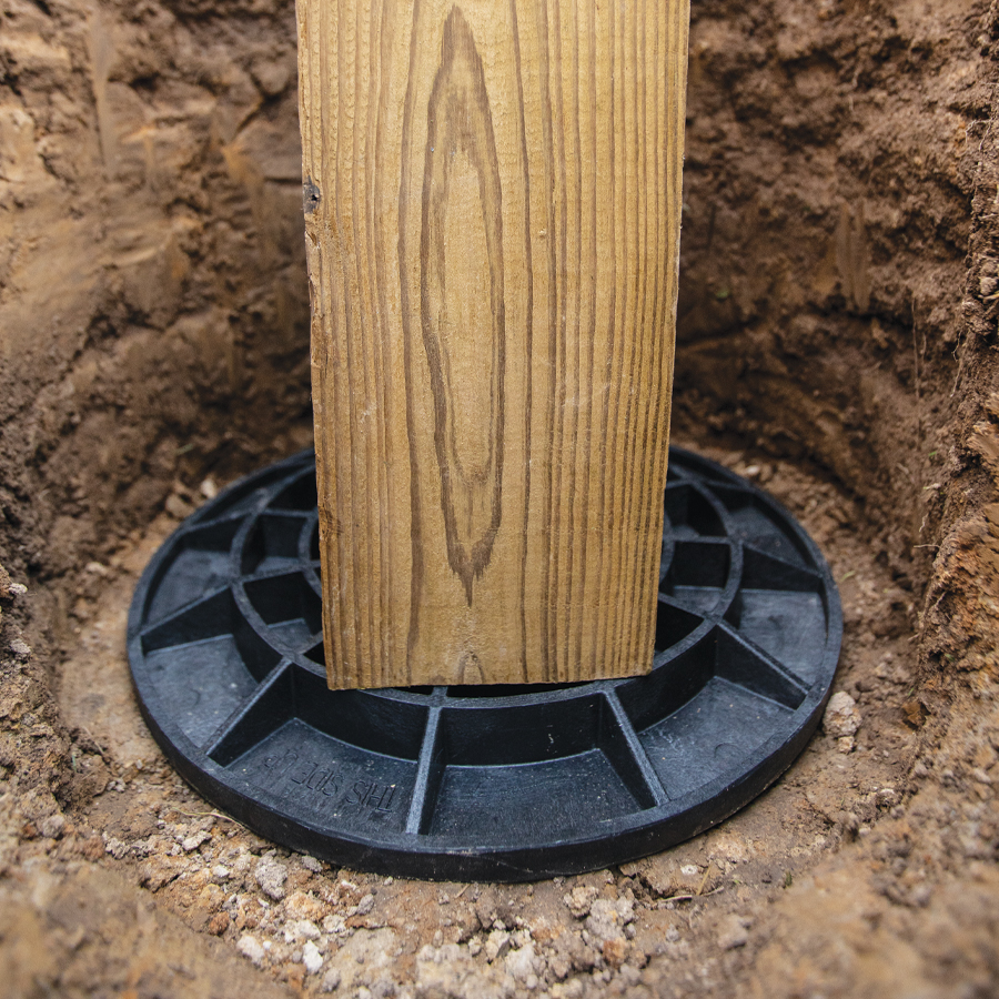 A wood post on a FootingPad foundation in a hole.