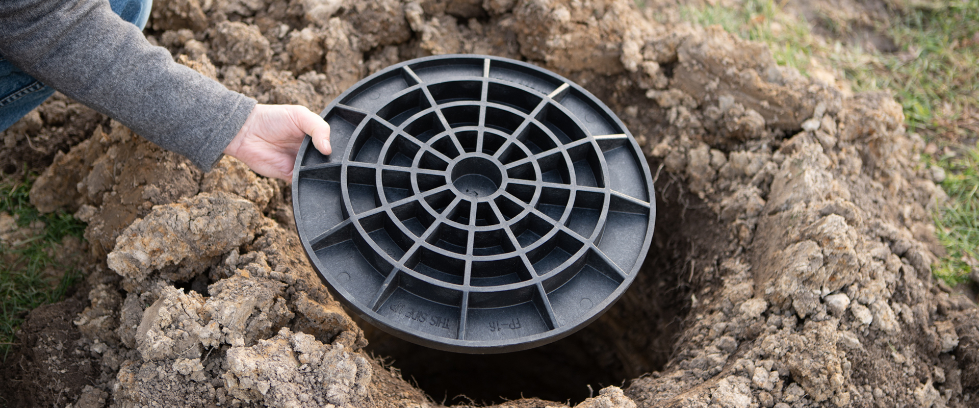 Hand holding a FootingPad as it is placed into a hole in the ground.