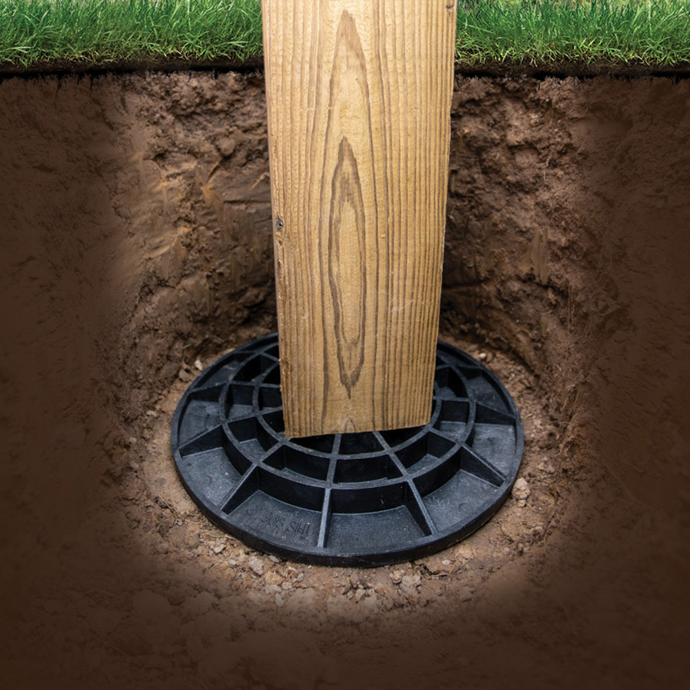 A treated wood post using a FootingPad as a foundation in a hole in the ground